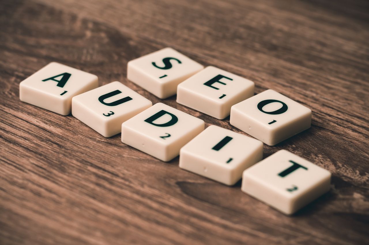 Scrabble tiles arranged to spell SEO Audit on a wooden surface, representing digital marketing strategies.